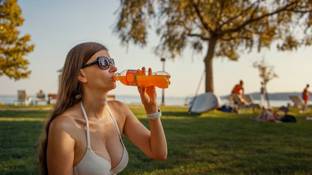 woman in white bikini top holding orange plastic bottle